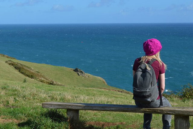 coast path with a girl on bench overlooking the sea.