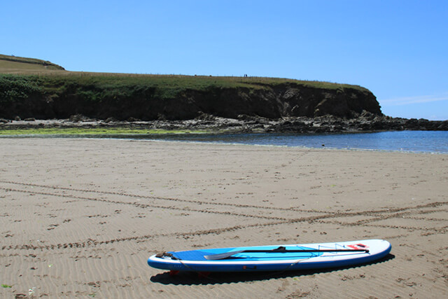 Watersports in Devon - paddleboard on the beach with blue skies.