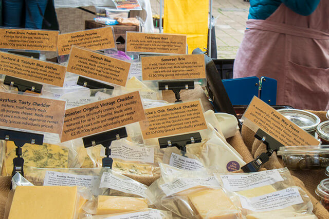 Buckfastleigh Farmers Market - a range of cheeses labelled on a market stall.