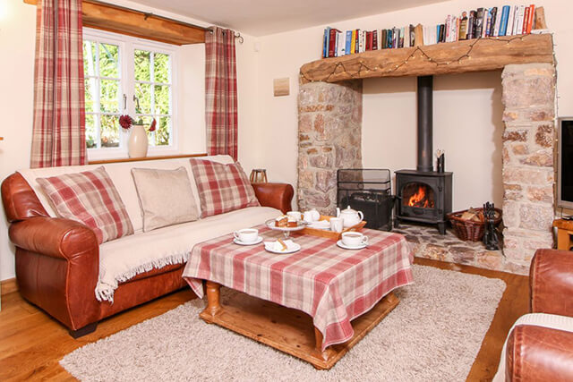 church thatch living room with sofas and log burner.