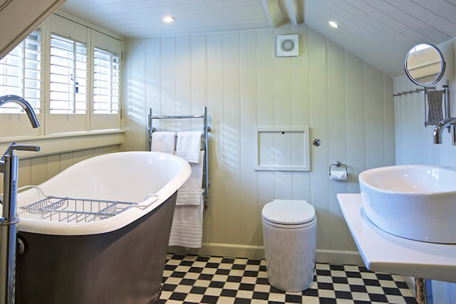 Berry cottage bathroom with clean towels, bath tub and sink with tiled floor.