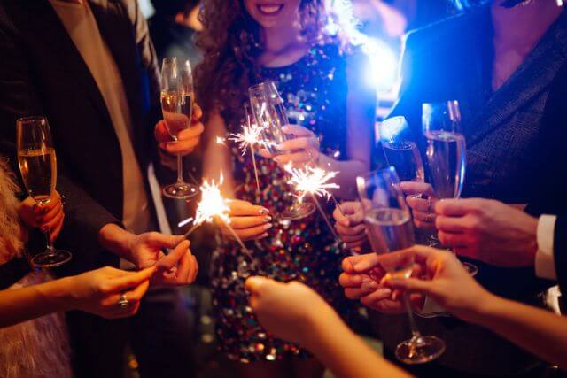 People toasting to the New Year with bubbly and sparklers.