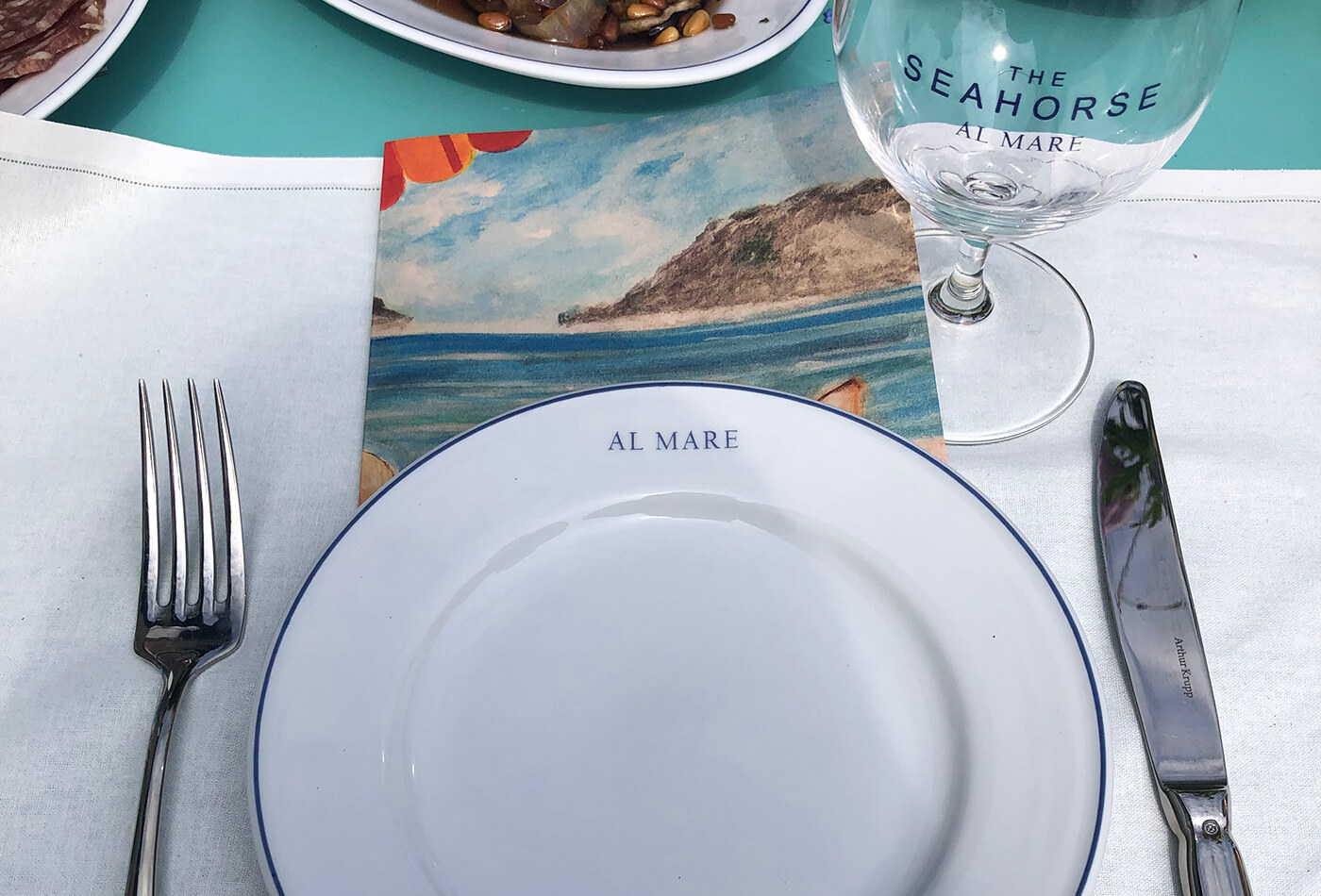 Seahorse Al Mare table setup with branded plate and glass.